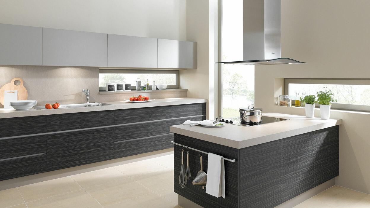 Impression einer Küchengestaltung mit Kochinsel mit Edelstahlabzug und dunklen Fronten
