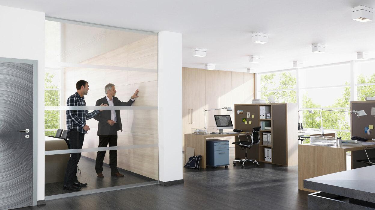 Impression eines Büros mit abgeschlossenem Raum mit Glaswand und offener Bürogestaltung.