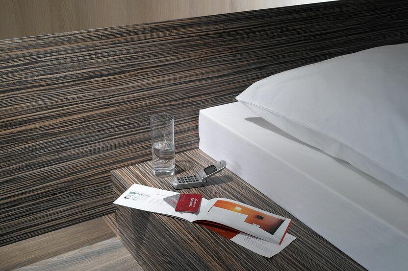 Detailaufnahme von Bettumrandung Detailaufnahme von Bettumrandung in dunklem Holz mit Ablagemöglichkeit